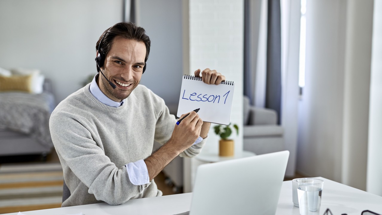 equipo. Un profesor dando clases en remoto con "Lesson 1" escrito en un bloc de notas