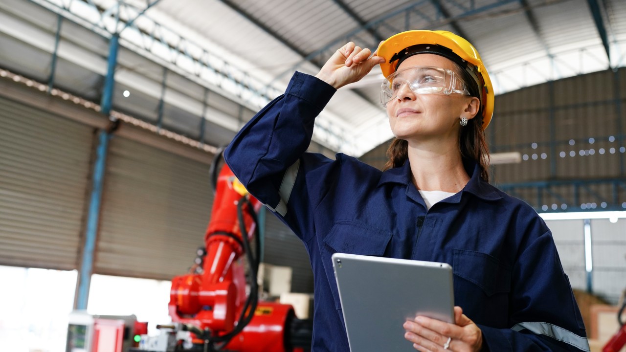 ingeniería de calidad. Una mujer con su mono de trabajo, casco y gafas de protección mientras sujeta una tablet