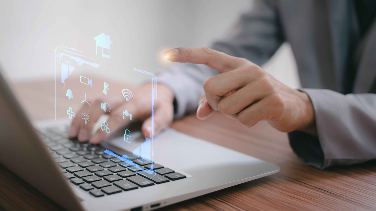 ofimática. Persona trabajando en un portátil mientras maneja un holograma con el dedo